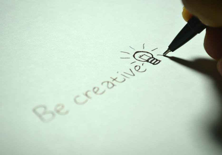 Close-up of handwritten 'Be creative' with a light bulb sketch on paper.
