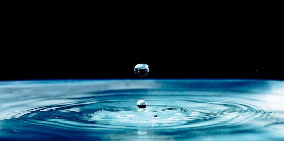 Captivating macro shot of a water droplet impacting a calm surface, showcasing detail and movement.