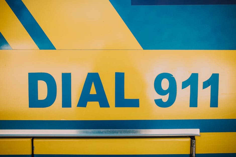 Close-up of 'Dial 911' emergency sign on a vehicle with bold yellow and blue colors.