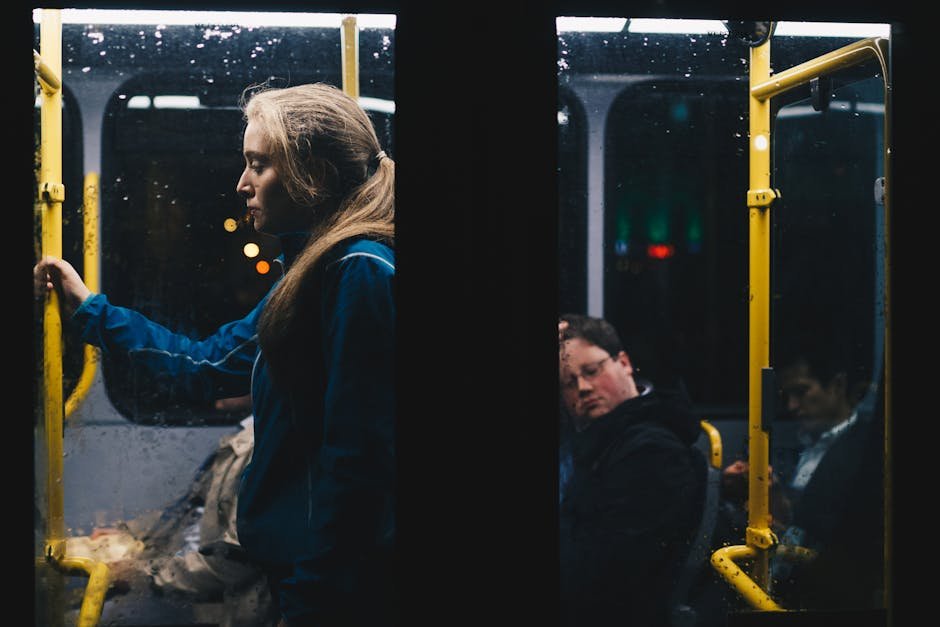 A solitary woman stands in a dimly lit Dublin city bus during a nightly commute.