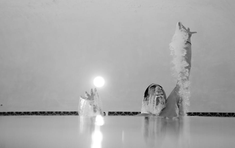 Captivating black and white photo of a swimmer emerging with water splashing dramatically.