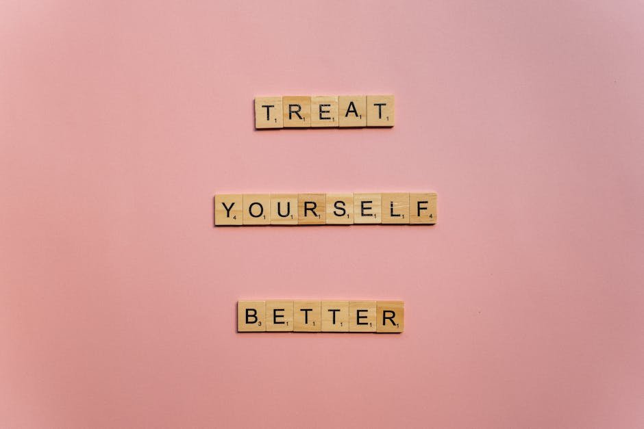 Wooden tiles on a pink background spelling 'Treat Yourself Better'. Ideal for self-care and motivation themes.